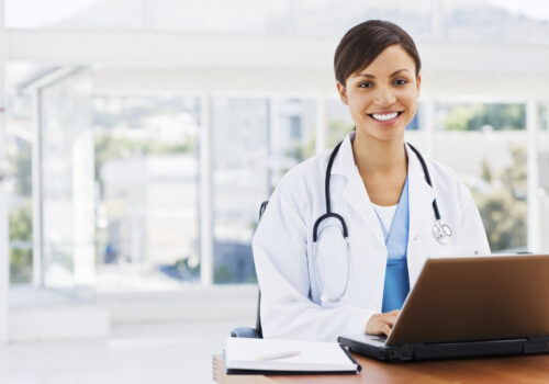 Happy beautiful female doctor sitting with a laptop