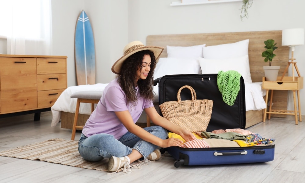 woman unpacking suitcase with clothes in hotel room